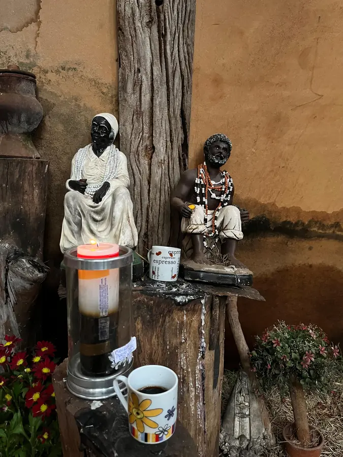 Imagens de pretos-velhos sobre um altar, com velas e oferendas.