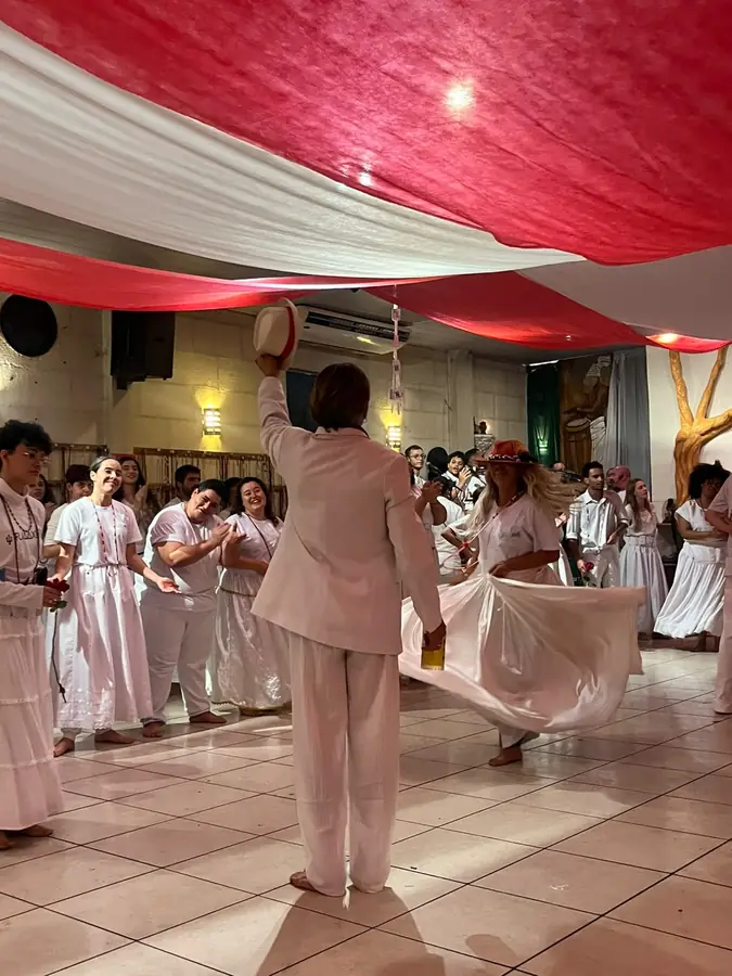 Médium de vestido lilás dançando sob uma tenda vermelha.