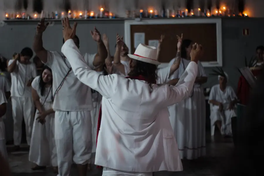 Grupo de médiuns de branco, de braços erguidos, durante uma gira.